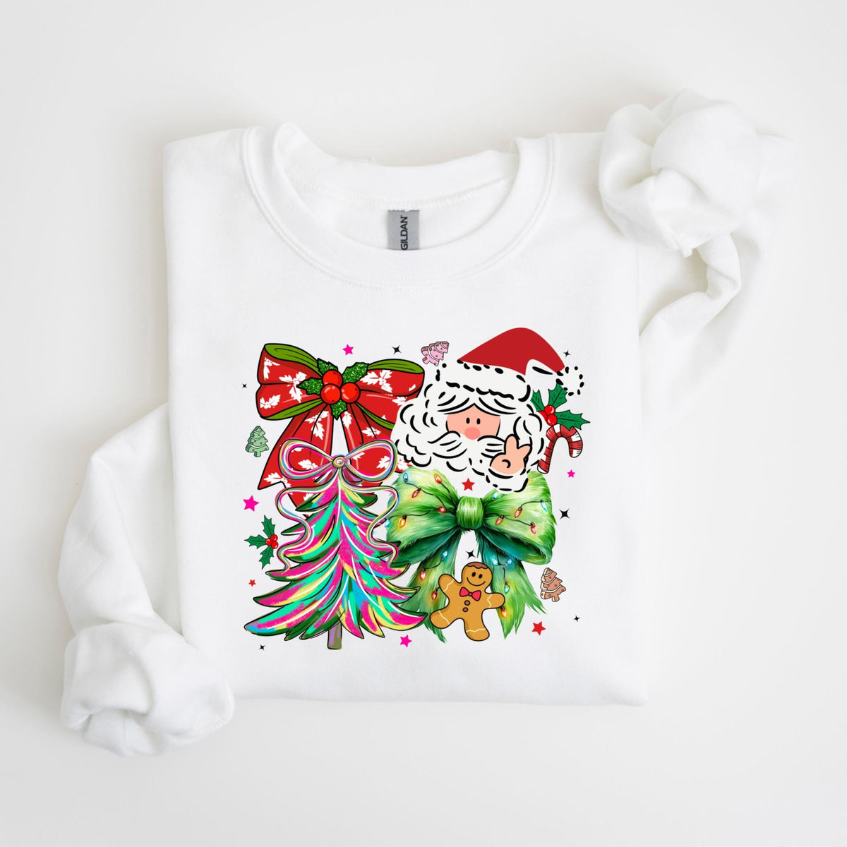 May include: White sweatshirt featuring a colorful Christmas design. The graphic includes Santa Claus, a gingerbread man, a Christmas tree, and bows. The design incorporates red, green, pink, and other bright colors, perfect for the holiday season.