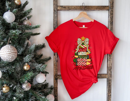 May include: A red t-shirt featuring a Christmas tree design made of stacked pencils. The pencils are decorated with various patterns and topped with a star and a bow. The text "Mrs. Smith" is written below the tree.