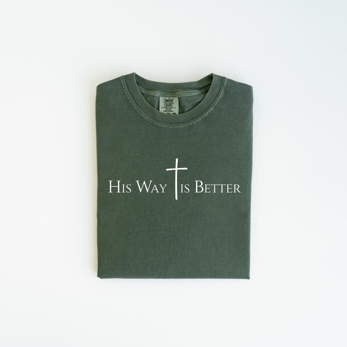 May include: A dark green t-shirt with the text "His Way Is Better" in white, along with a white cross. The shirt is folded neatly and is displayed on a white background. The shirt is made of a soft material.
