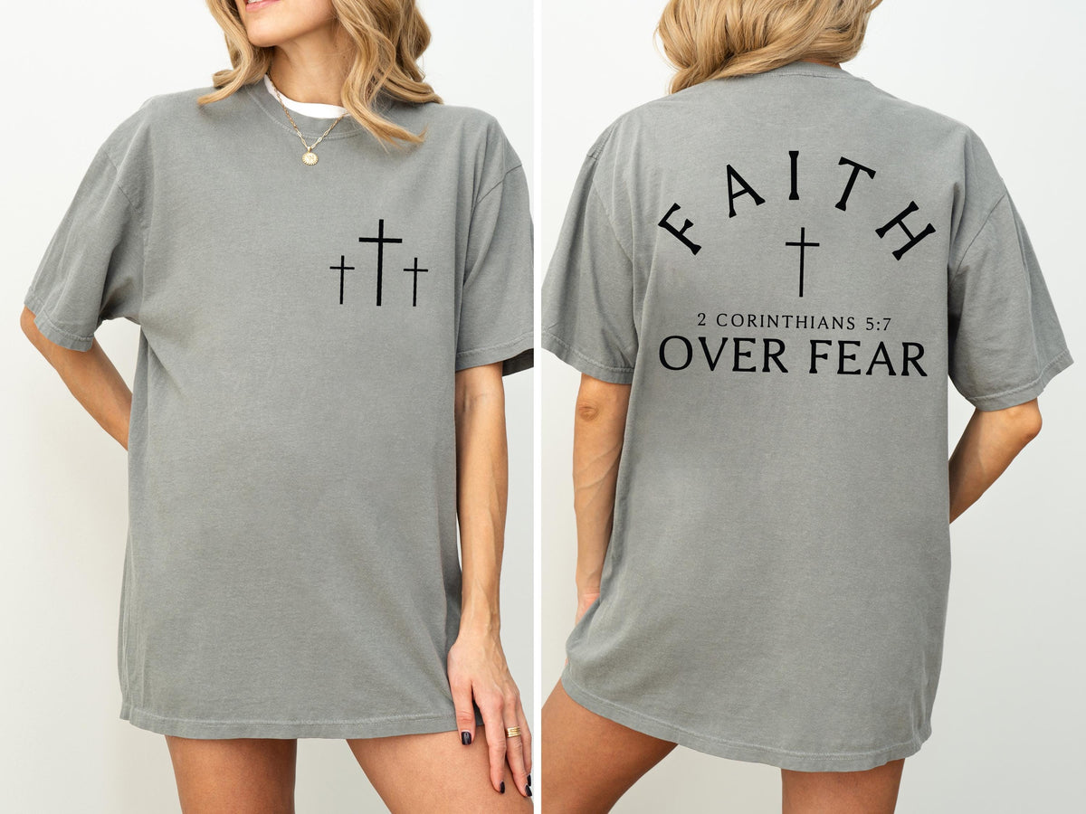 May include: A gray t-shirt with three black crosses on the front and the text "FAITH OVER FEAR" with a cross and the Bible verse 2 Corinthians 5:7 on the back. The shirt is a casual, oversized style.
