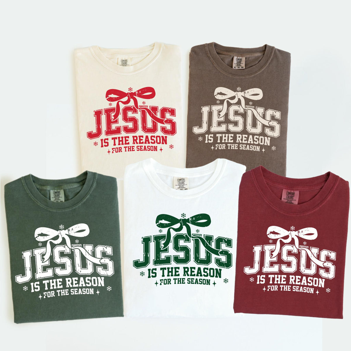 May include: Five t-shirts in various colors, each featuring the text "JESUS IS THE REASON FOR THE SEASON" in a festive design. The shirts are in cream, brown, green, white, and burgundy.