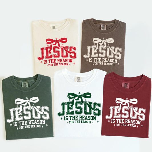 May include: Five t-shirts in various colors, each featuring the text "JESUS IS THE REASON FOR THE SEASON" in a festive design. The shirts are in cream, brown, green, white, and burgundy.