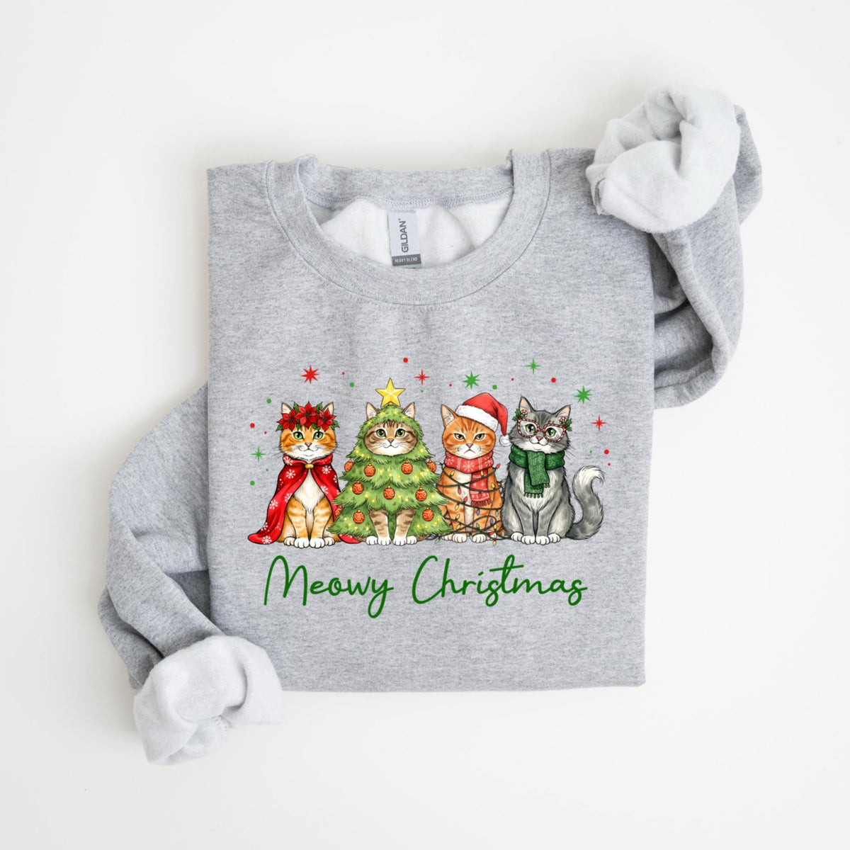 May include: A gray sweatshirt featuring four cats dressed for Christmas. One cat wears a red cape and wreath, another is a Christmas tree, and the others wear a Santa hat and scarf. The words "Meowy Christmas" are written in green.