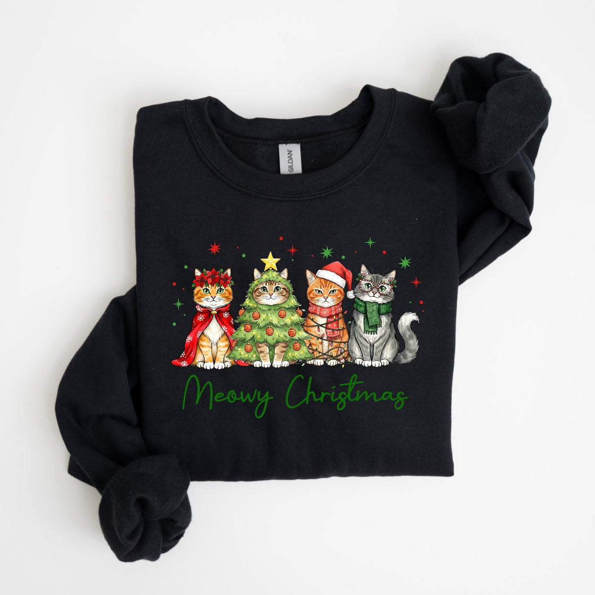 May include: Black sweatshirt featuring a festive design with four cats dressed for Christmas. One cat wears a cape, another is a Christmas tree, and two others wear scarves and hats. The words "Meowy Christmas" are written in green.
