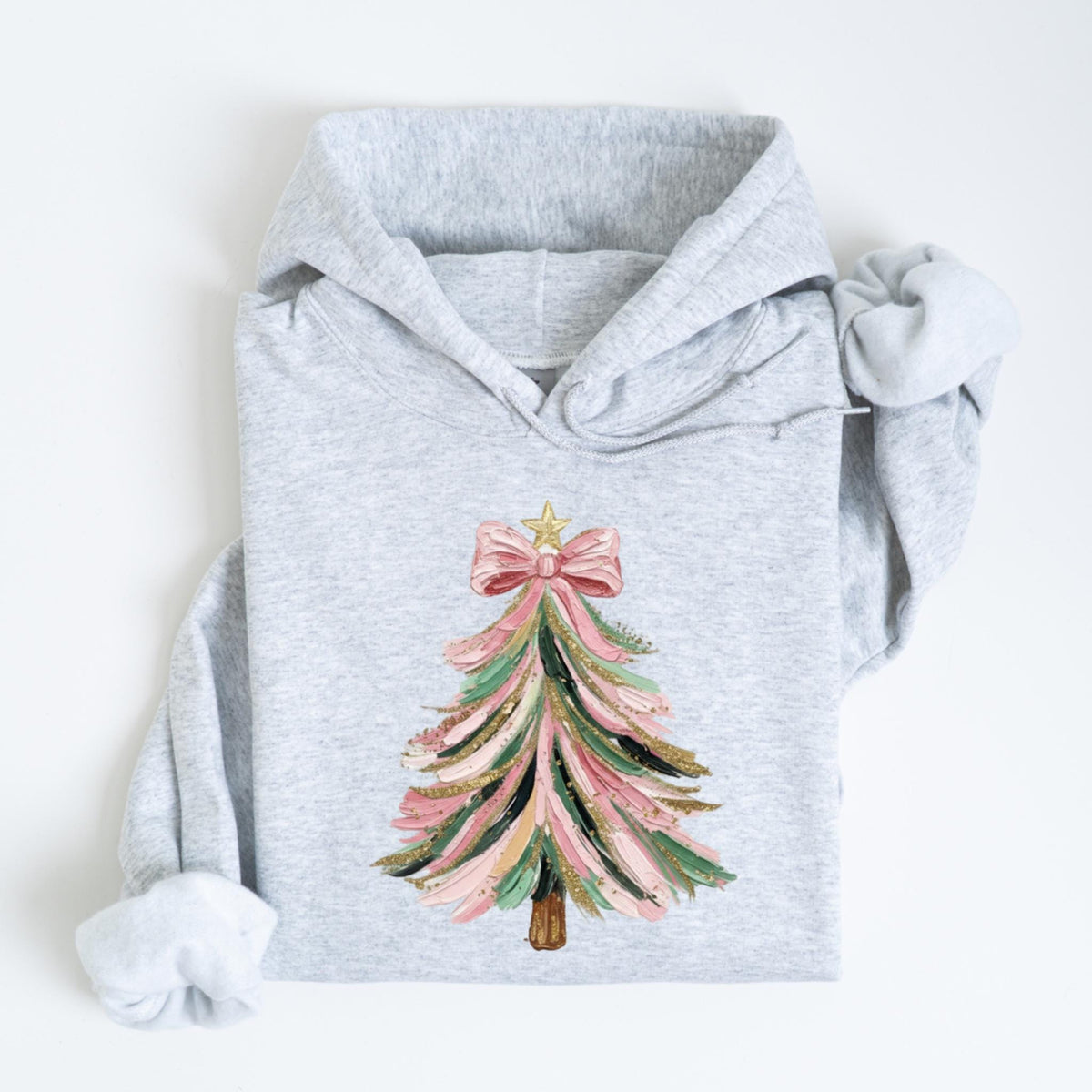May include: A light gray hoodie featuring a Christmas tree design. The tree is decorated with pink, green, and gold brushstrokes, topped with a pink bow and a gold star. The hoodie has a drawstring hood and long sleeves.