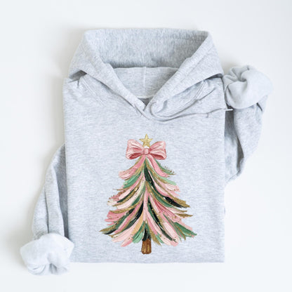 May include: A light gray hoodie featuring a Christmas tree design. The tree is decorated with pink, green, and gold brushstrokes, topped with a pink bow and a gold star. The hoodie has a drawstring hood and long sleeves.