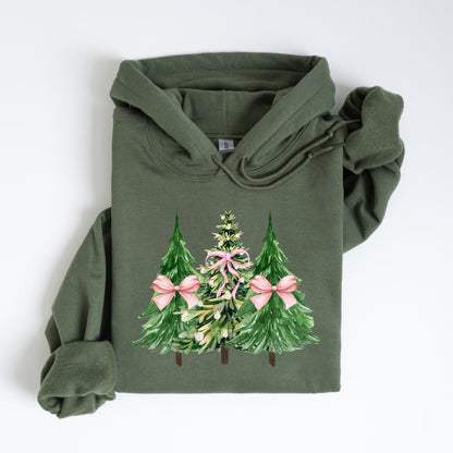 May include: Olive green hoodie featuring a watercolor design of three Christmas trees. The trees are green with pink bows and a central tree with pink accents. The hoodie has a drawstring hood and long sleeves, perfect for the holiday season.