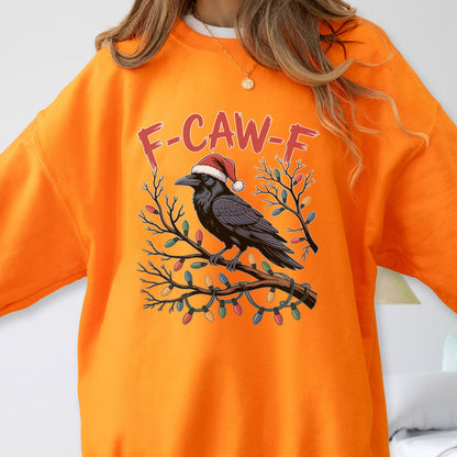 May include: A bright orange crewneck sweatshirt featuring a graphic of a black raven wearing a red and white Santa hat, perched on a branch wrapped in colorful Christmas lights, with the red text F-CAW-F printed in an arched design above.