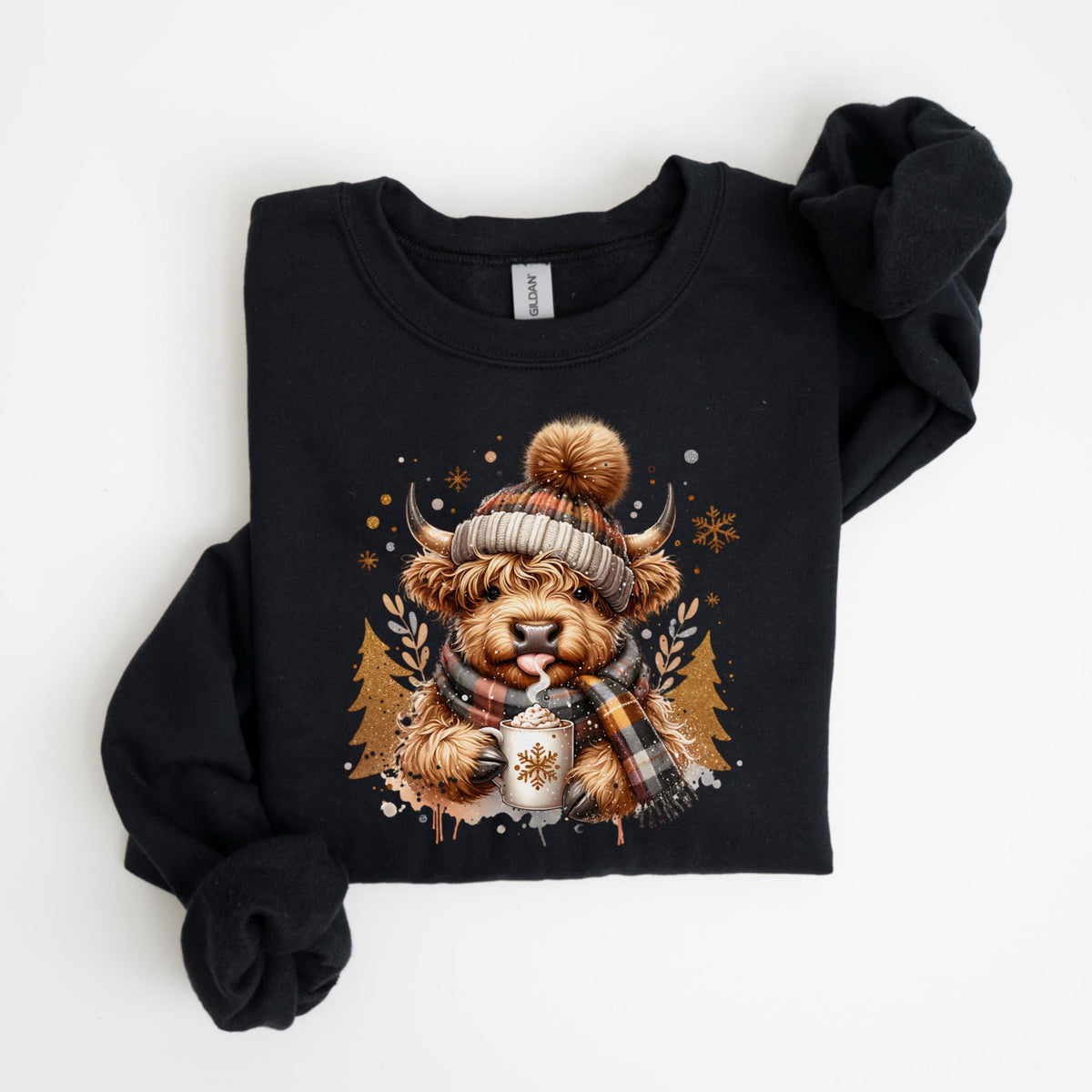 May include: Black sweatshirt featuring a Highland cow illustration. The cow is wearing a plaid scarf and a knit hat with a pom-pom, holding a mug with a snowflake design. The design includes snowflakes and pine trees.