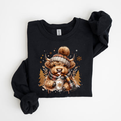 May include: Black sweatshirt featuring a Highland cow illustration. The cow is wearing a plaid scarf and a knit hat with a pom-pom, holding a mug with a snowflake design. The design includes snowflakes and pine trees.