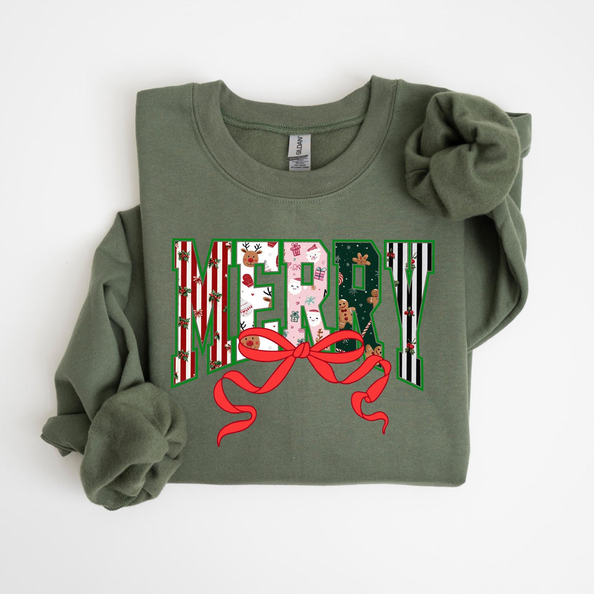 May include: An olive green sweatshirt with the word "MERRY" in a festive design. The letters are filled with Christmas-themed patterns, including reindeer, gifts, and gingerbread men, and are accented with a red bow.