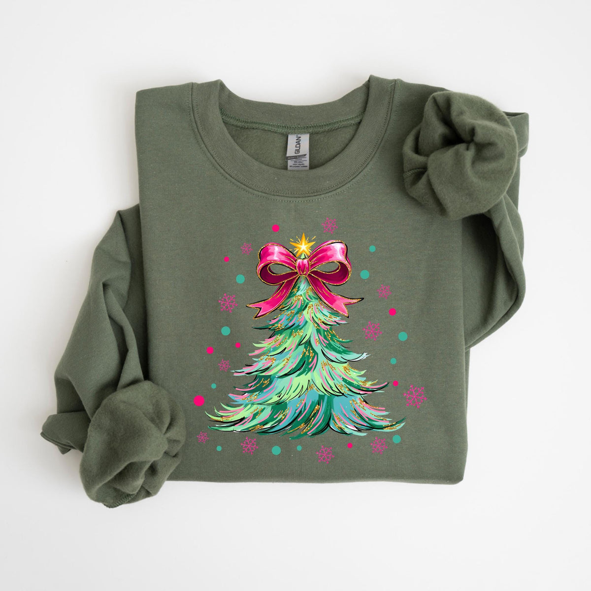 May include: Olive green sweatshirt featuring a Christmas tree design. The tree is decorated with a pink bow, a gold star, and colorful accents. The design includes pink snowflakes and teal dots, creating a festive holiday theme.