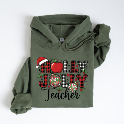 May include: An olive green hoodie with the words "Holly Jolly Teacher" in a festive design. The design includes a Santa hat, apple, plaid letters, and Christmas ornaments, perfect for the holiday season.
