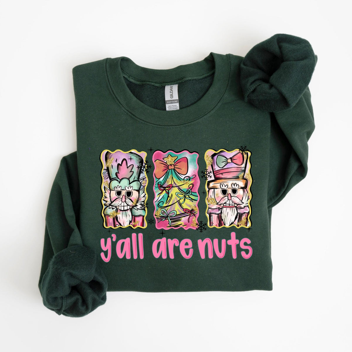 May include: Dark green sweatshirt with a graphic that says "y'all are nuts." The graphic features three colorful images of nutcrackers and a Christmas tree. The sweatshirt is made of a soft material.