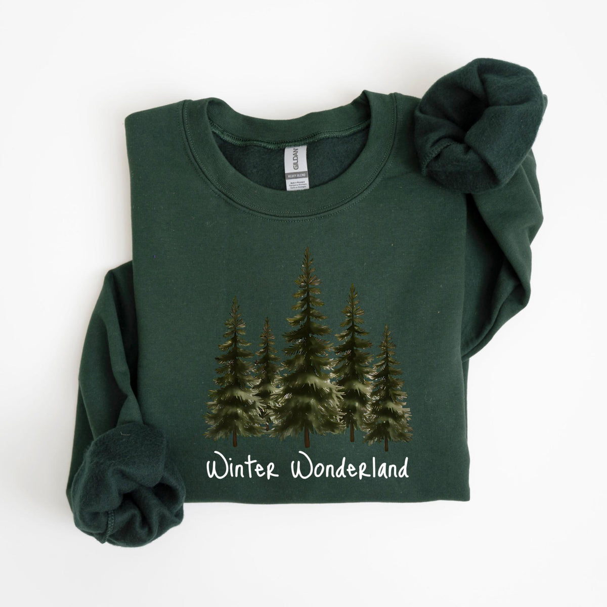 May include: Dark green sweatshirt with a crew neck. The front features a watercolor illustration of evergreen trees and the words "Winter Wonderland" in a script font. The sleeves are folded.