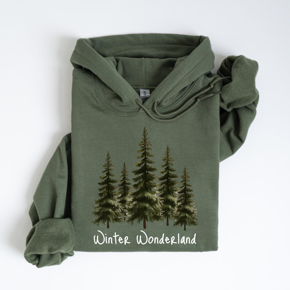 May include: An olive green hoodie featuring a watercolor illustration of evergreen trees. The phrase "Winter Wonderland" is printed in white script at the bottom of the design. The hoodie has a drawstring hood and long sleeves.