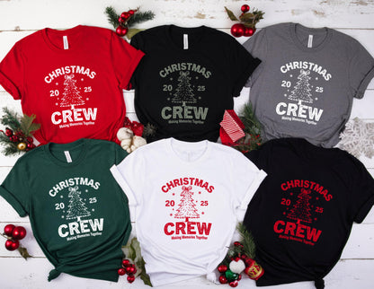 May include: A collection of Christmas Crew t-shirts in various colors, including red, black, white, green, gray, and black. Each shirt features a Christmas tree graphic with the text "CHRISTMAS 20 25 CREW Making Memories Together" in a contrasting color.