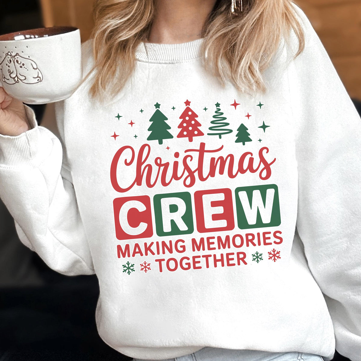 May include: A white crewneck sweatshirt featuring a festive graphic with red and green text that reads Christmas CREW MAKING MEMORIES TOGETHER, accented by illustrations of four stylized Christmas trees and small star and snowflake icons.
