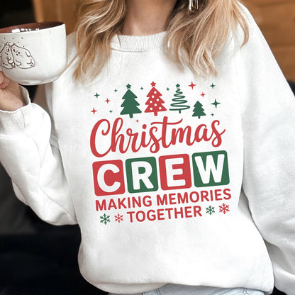 May include: A white crewneck sweatshirt featuring a festive graphic with red and green text that reads Christmas CREW MAKING MEMORIES TOGETHER, accented by illustrations of four stylized Christmas trees and small star and snowflake icons.