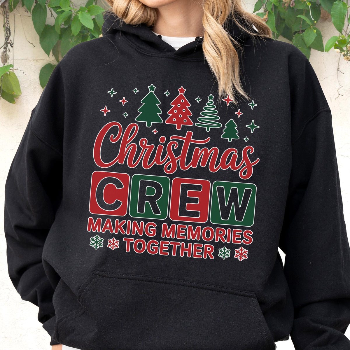May include: A black hooded sweatshirt featuring a graphic print with the text Christmas CREW MAKING MEMORIES TOGETHER. The design includes red and green Christmas trees, snowflakes, and stars in a festive holiday style on the front chest.