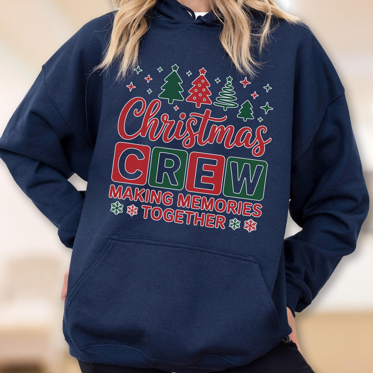 May include: A navy blue hooded sweatshirt featuring a graphic print with the text "Christmas CREW MAKING MEMORIES TOGETHER" in red, green, and white. The design includes small illustrations of Christmas trees and snowflakes above and below.