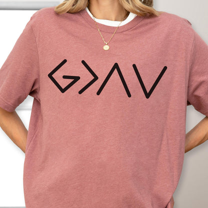 May include: A dusty rose short-sleeved t-shirt featuring a black graphic print of the symbols G > ^ v. The shirt has a crew neckline and is worn with a gold chain necklace featuring a small circular pendant resting against the collarbone area.