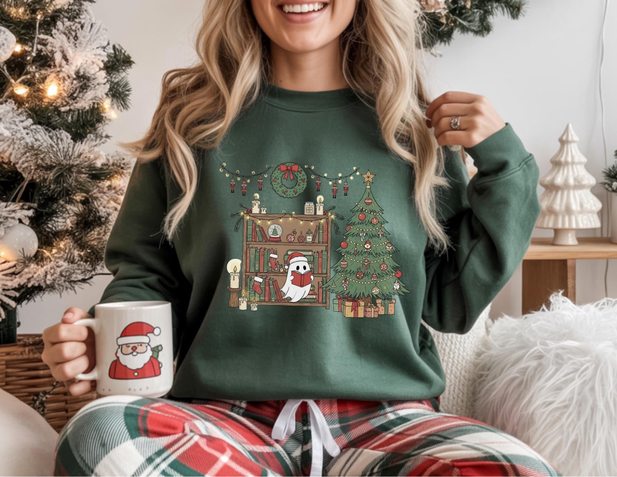 May include: A dark green sweatshirt with a Christmas-themed graphic. The graphic features a decorated Christmas tree, a bookshelf with candles and books, and a ghost wearing a Santa hat. A white mug with a Santa Claus illustration is held in the hand.