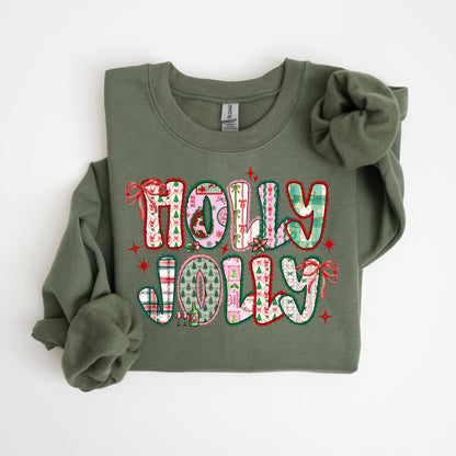 May include: Olive green sweatshirt with the words "HOLLY JOLLY" in a colorful, patchwork design. The letters are filled with festive patterns, including plaid, Christmas trees, and bows, perfect for the holiday season.