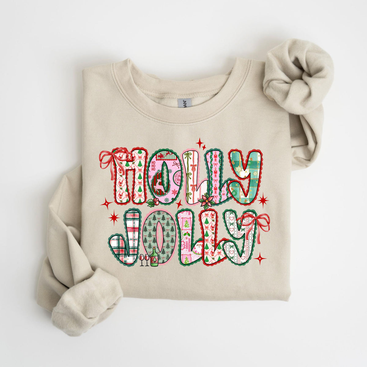 May include: A beige sweatshirt with the words "HOLLY JOLLY" in a colorful, patterned design. The letters are outlined in green and red, with various holiday-themed patterns inside, including plaid, trees, and bows. Red stars and bows accent the design.