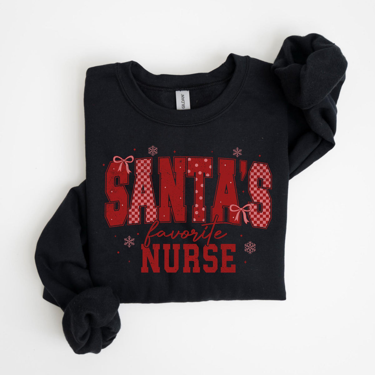 May include: Black sweatshirt with the text "SANTA'S favorite NURSE" in red. The text has a mix of patterns, including polka dots and a checkered design. The sweatshirt is folded, with the sleeves visible.