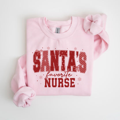 May include: A light pink sweatshirt with the text "SANTA'S favorite NURSE" in red. The text has a checkered pattern and is decorated with bows and snowflakes. The sweatshirt is a crew neck style.