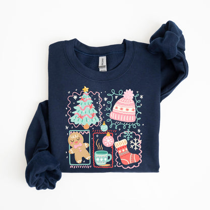 May include: Navy blue sweatshirt featuring a colorful Christmas-themed graphic. The design includes a Christmas tree, a pink beanie, a gingerbread man, a mug of hot cocoa, and a Christmas stocking. The graphic is framed with decorative borders and snowflakes.