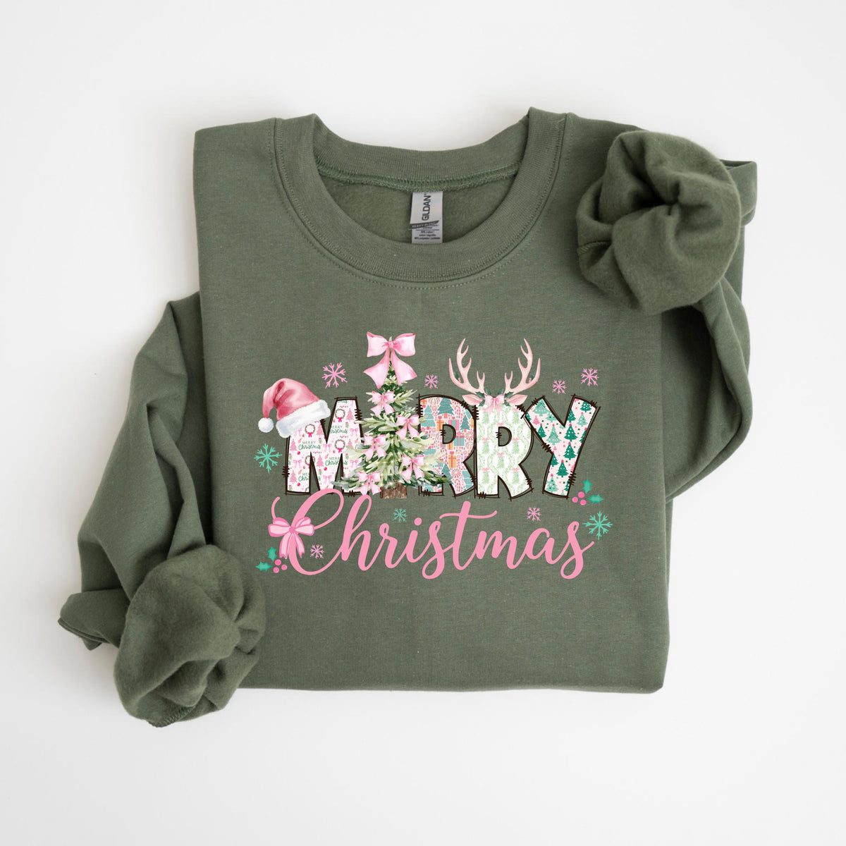 May include: Olive green sweatshirt with a festive "Merry Christmas" design. The graphic includes a Christmas tree, reindeer antlers, snowflakes, and a Santa hat. The text is in pink and white, creating a holiday theme.