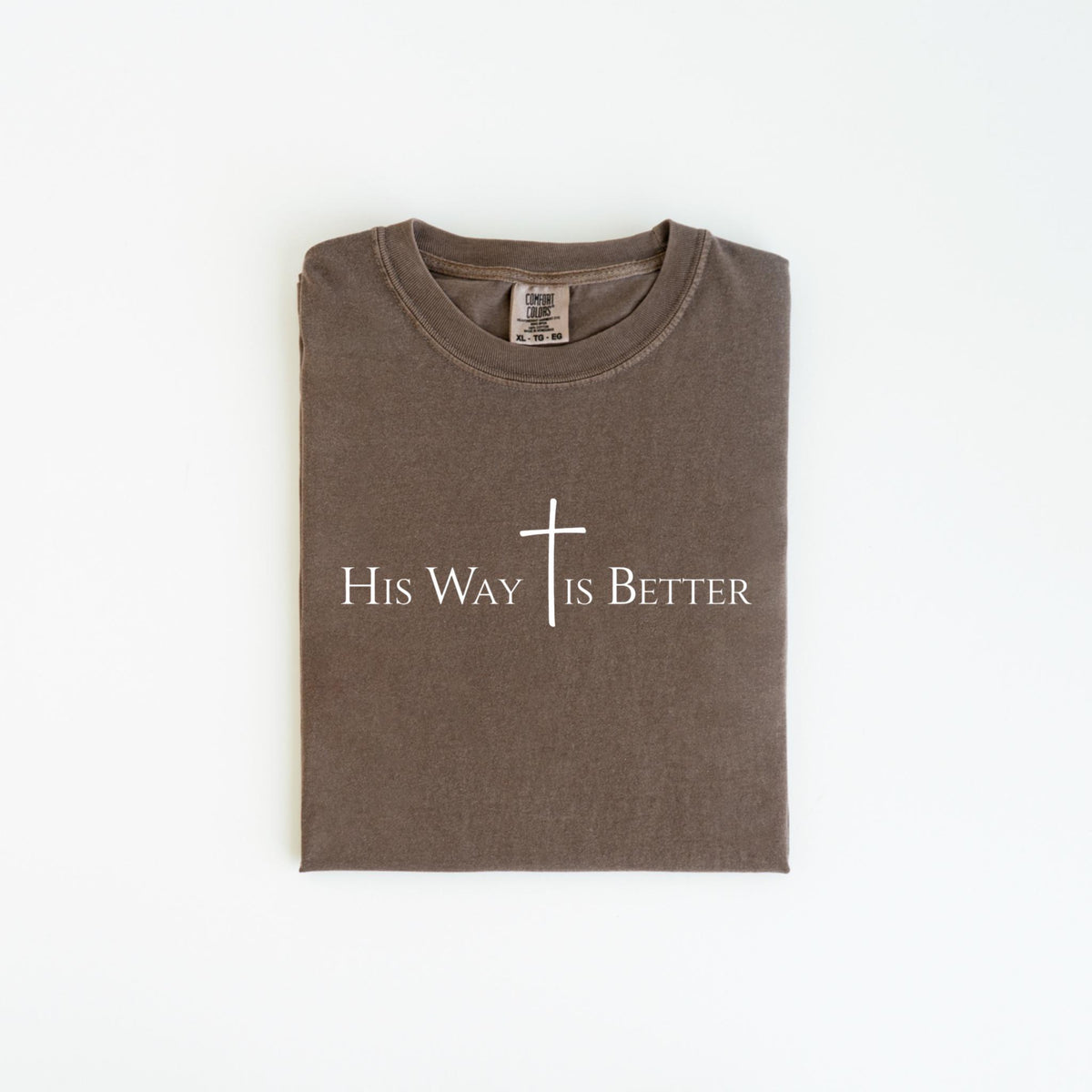 May include: A folded, brown t-shirt with the text "His Way Is Better" and a white cross graphic. The shirt is made of a soft material and has a crew neck.