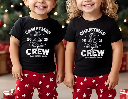May include: Two children wearing matching black t-shirts with a white Christmas tree graphic and the text "CHRISTMAS CREW". They are also wearing red pants with white star patterns. The phrase "Making Memories Together" is printed below the word "CREW".