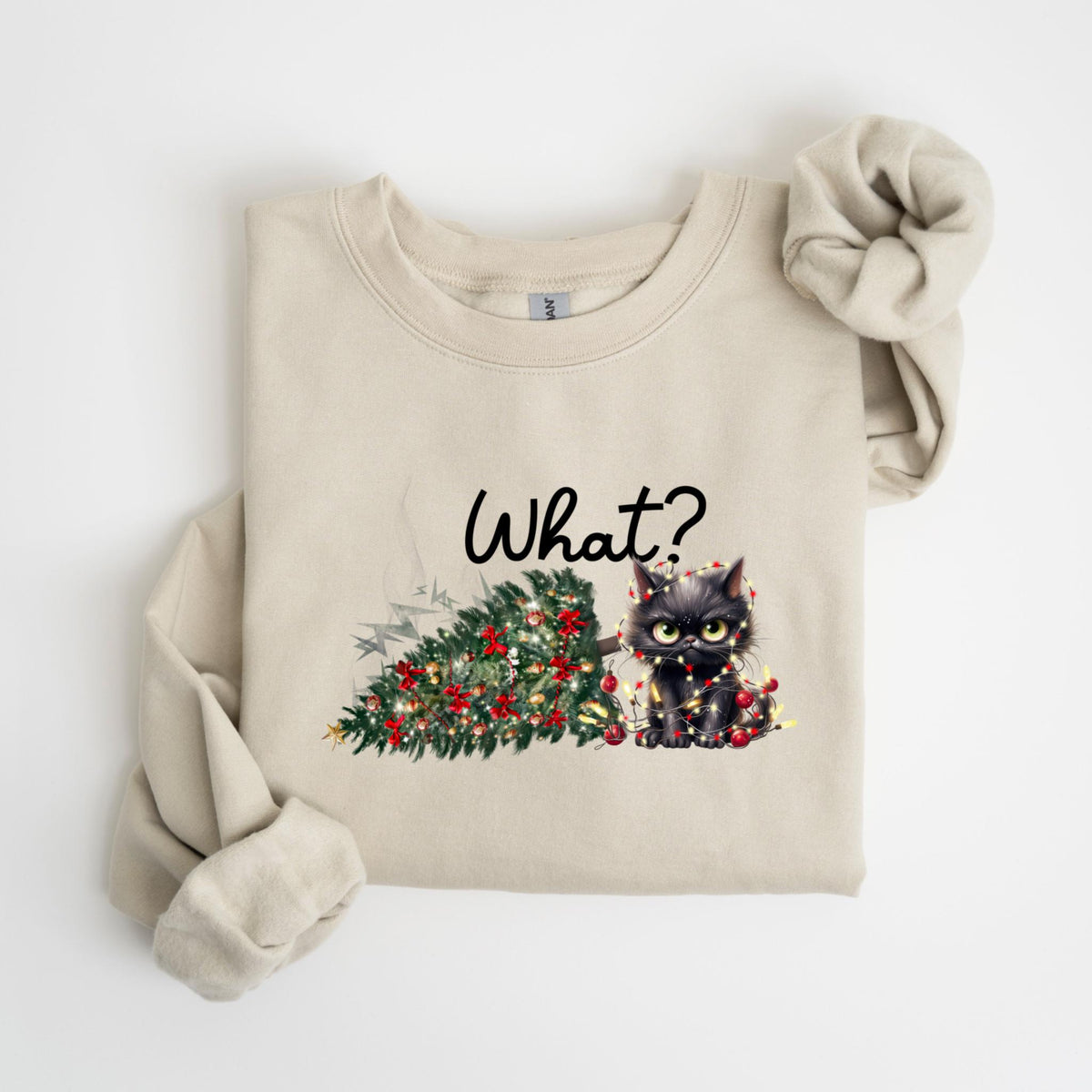 May include: A beige sweatshirt with a graphic of a black cat tangled in Christmas lights next to a fallen Christmas tree. The word "What?" is written above the cat in black script.