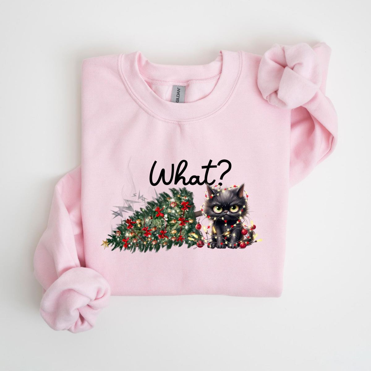 May include: A light pink sweatshirt featuring a graphic of a black cat tangled in Christmas lights next to a fallen Christmas tree. The word "What?" is written above the cat in black script.