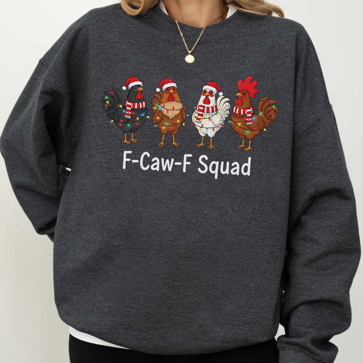 May include: Dark gray sweatshirt featuring a festive design. The graphic includes four cartoon chickens wearing Santa hats, scarves, and Christmas lights. The text "F-Caw-F Squad" is printed below the chickens.