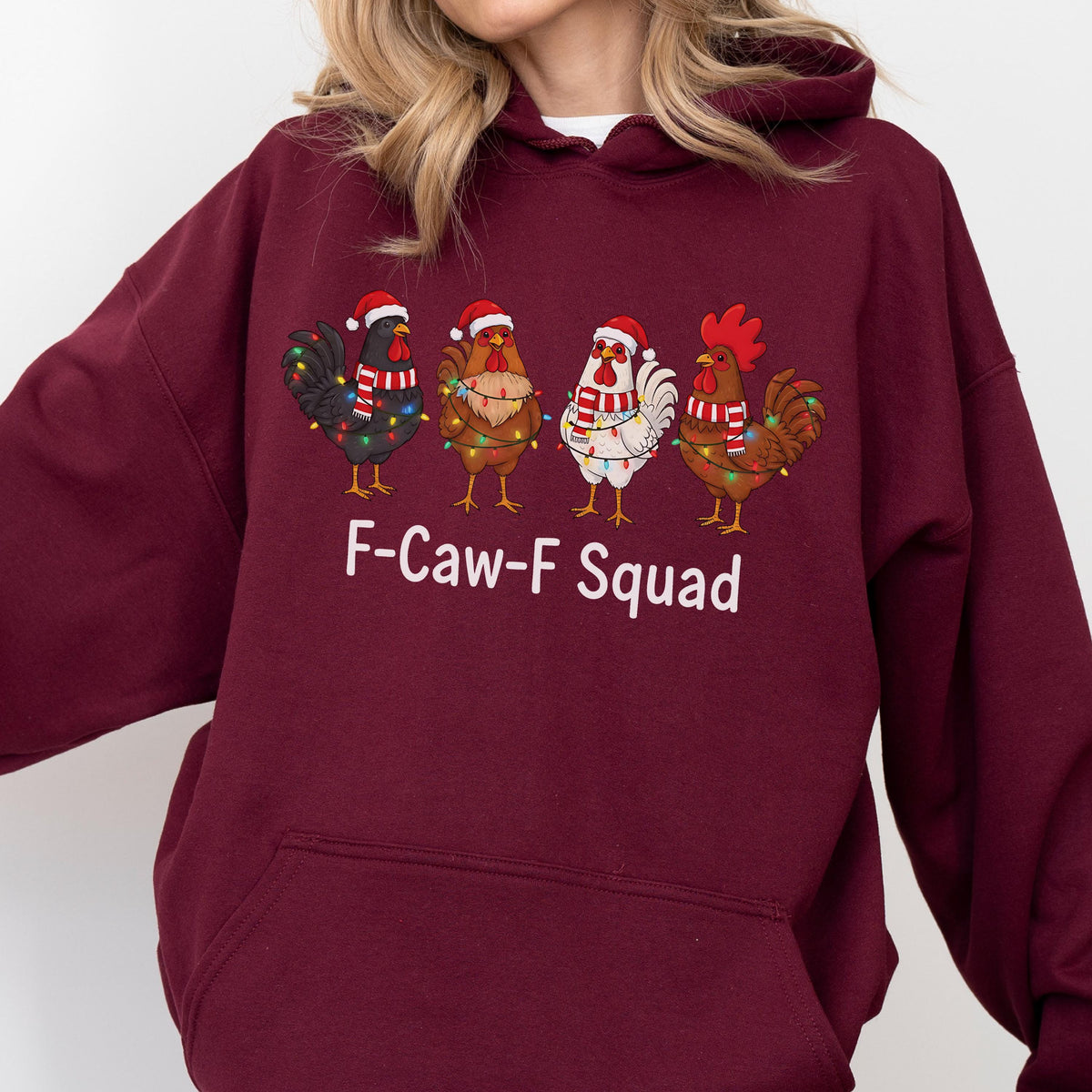 May include: A maroon hoodie featuring a graphic of four cartoon chickens wearing Santa hats and wrapped in Christmas lights. The text "F-Caw-F Squad" is printed below the chickens.