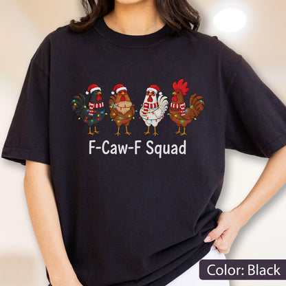 May include: Black t-shirt featuring a graphic of four chickens wearing Santa hats and scarves, adorned with Christmas lights. The text "F-Caw-F Squad" is printed below the chickens. The shirt is a solid black color.