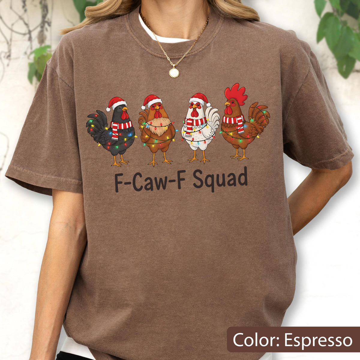 May include: Espresso-colored t-shirt featuring a graphic of four cartoon roosters wearing Santa hats and scarves, adorned with Christmas lights. The text "F-Caw-F Squad" is printed below the roosters. The shirt has a crew neck and short sleeves.
