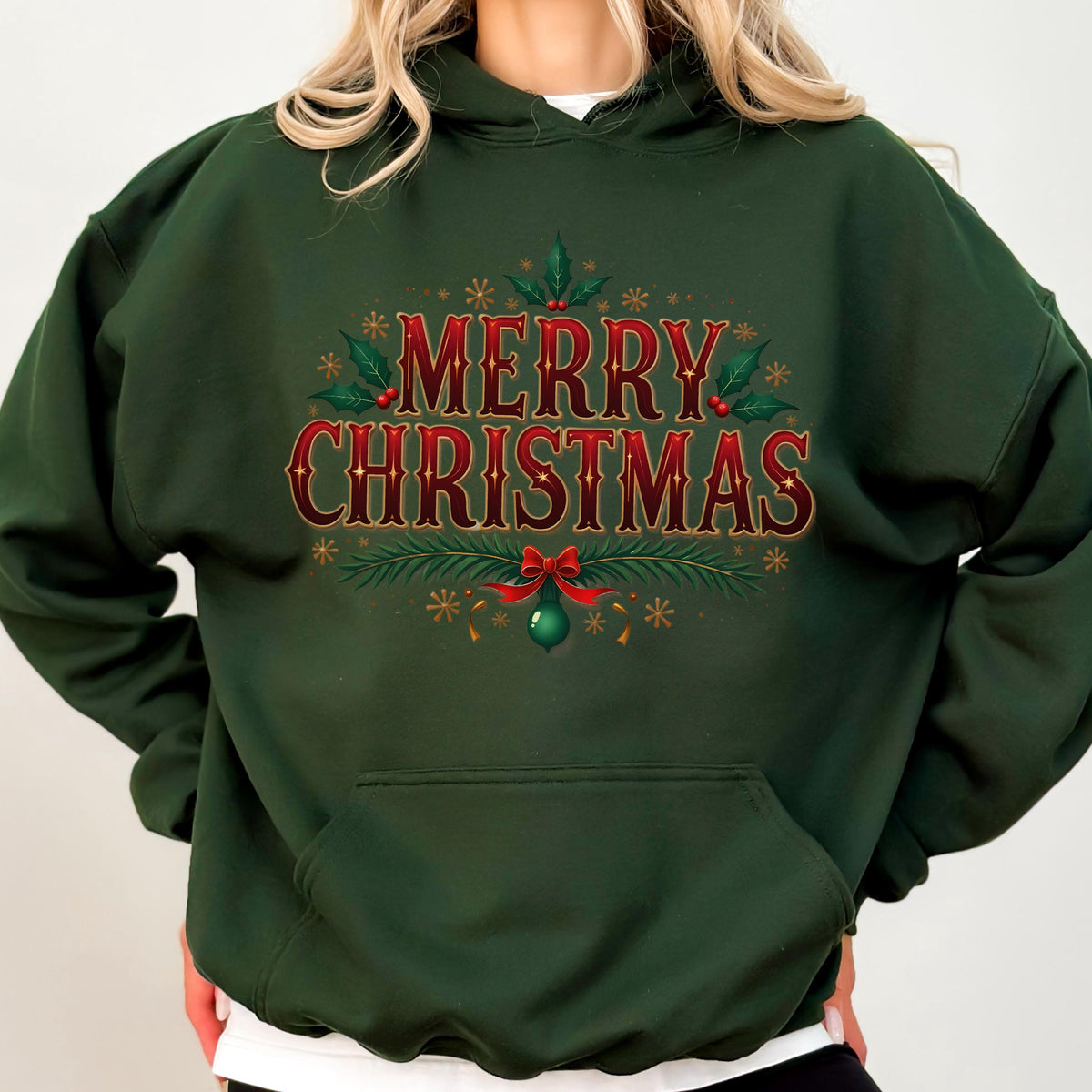 May include: Dark green hooded sweatshirt with the text "MERRY CHRISTMAS" in red and gold. The design includes holly leaves, berries, snowflakes, and a red bow. A green ornament hangs below the text.