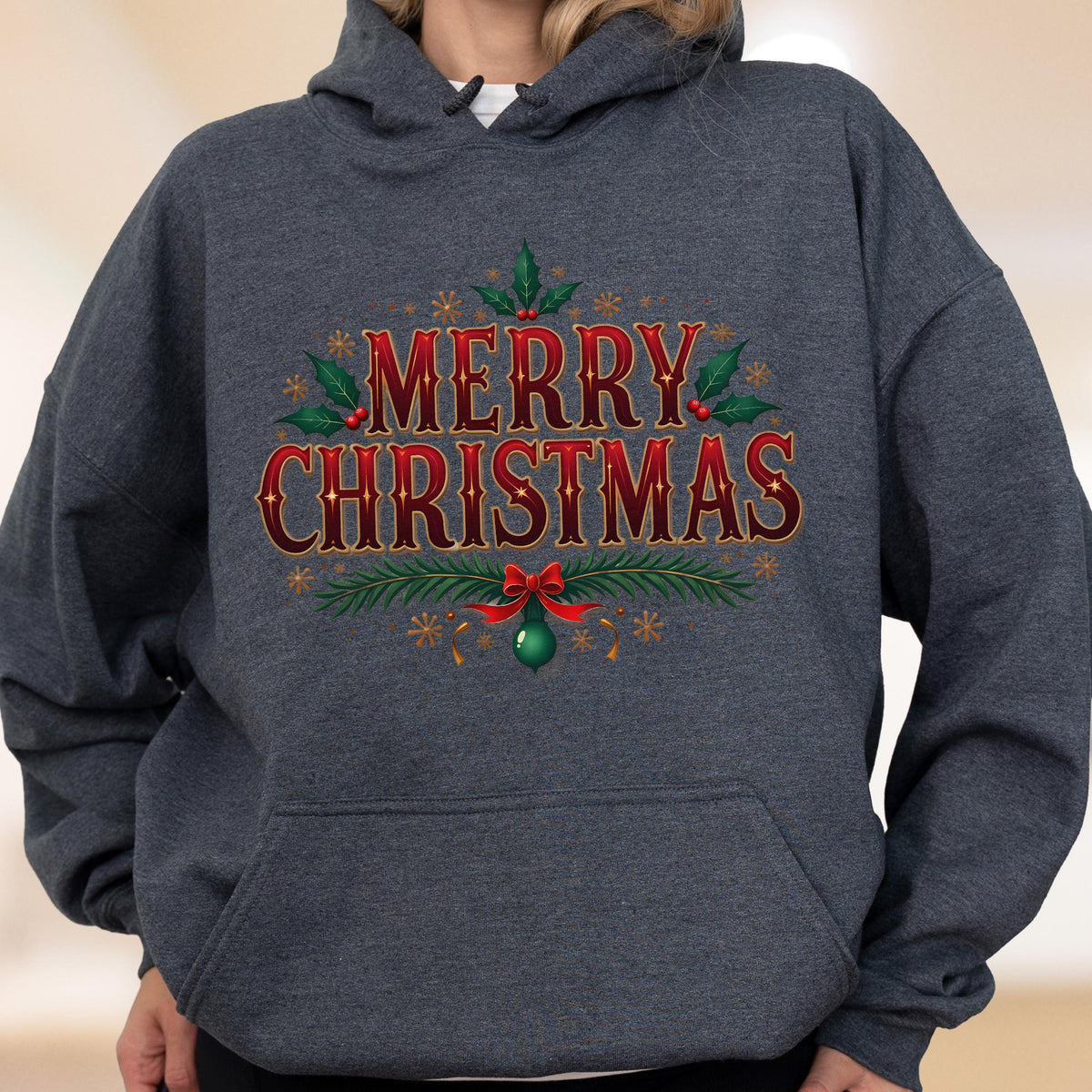 May include: A dark gray hoodie with the words "MERRY CHRISTMAS" in red and gold lettering. The design includes holly leaves, berries, snowflakes, and a green ornament with a red bow. A festive holiday apparel item.