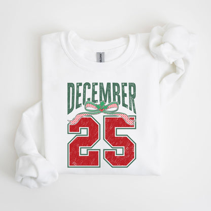 May include: White sweatshirt with the text "DECEMBER 25" in green and red. The text is designed with a distressed, vintage look, and includes a decorative bow with holly leaves.