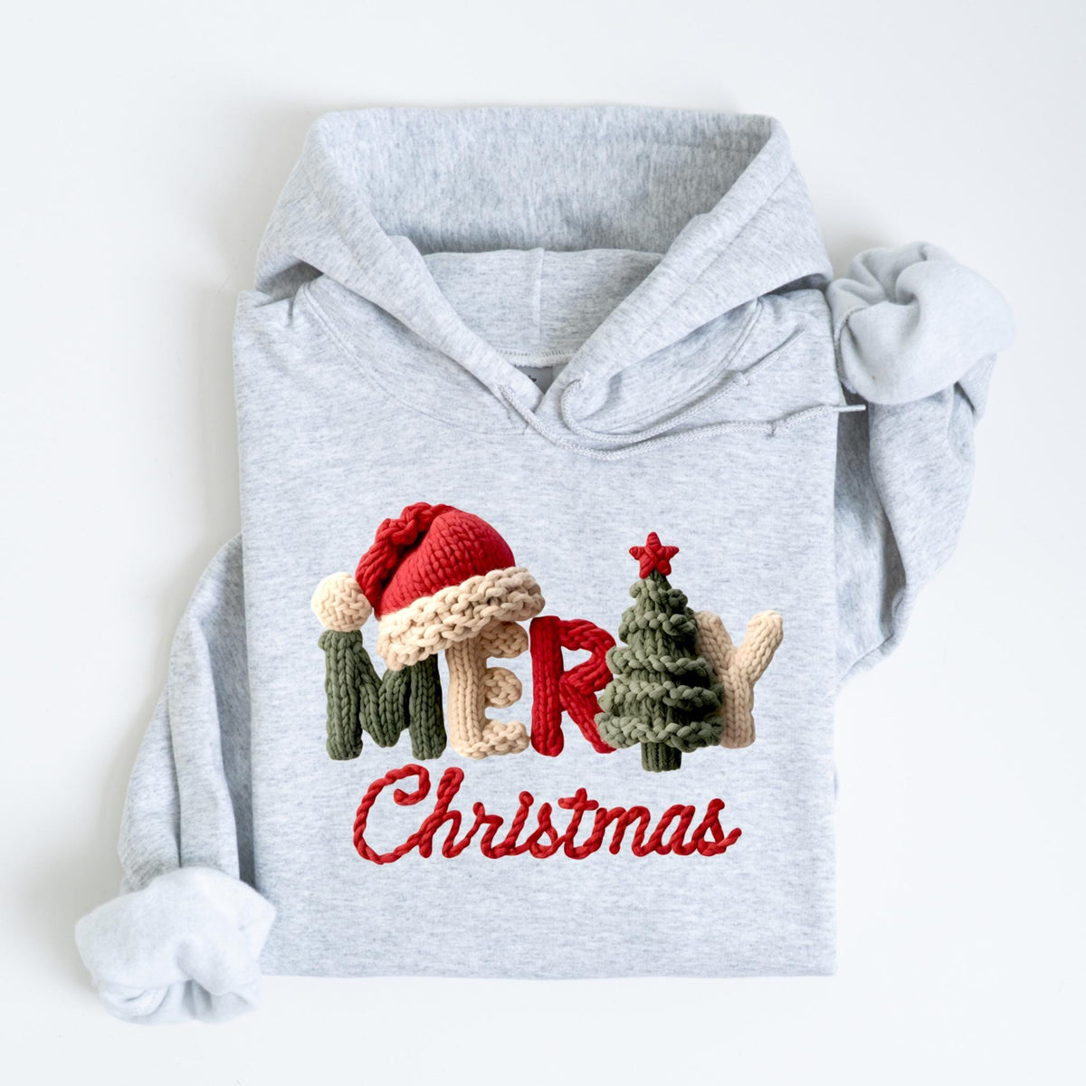May include: A light gray hoodie with the words "Merry Christmas" in red script. The letters are decorated with a Santa hat, a Christmas tree, and other festive elements, all in a knitted style.