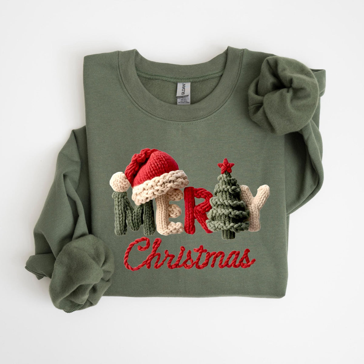 May include: Olive green sweatshirt with the word "MERRY" spelled out with a knitted Santa hat, a Christmas tree, and mittens. The word "Christmas" is embroidered in red script below.