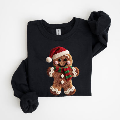 May include: Black crewneck sweatshirt featuring a gingerbread man design. The gingerbread man wears a red Santa hat and a red and green striped scarf. The gingerbread man has a smiling face and two white snowflakes.