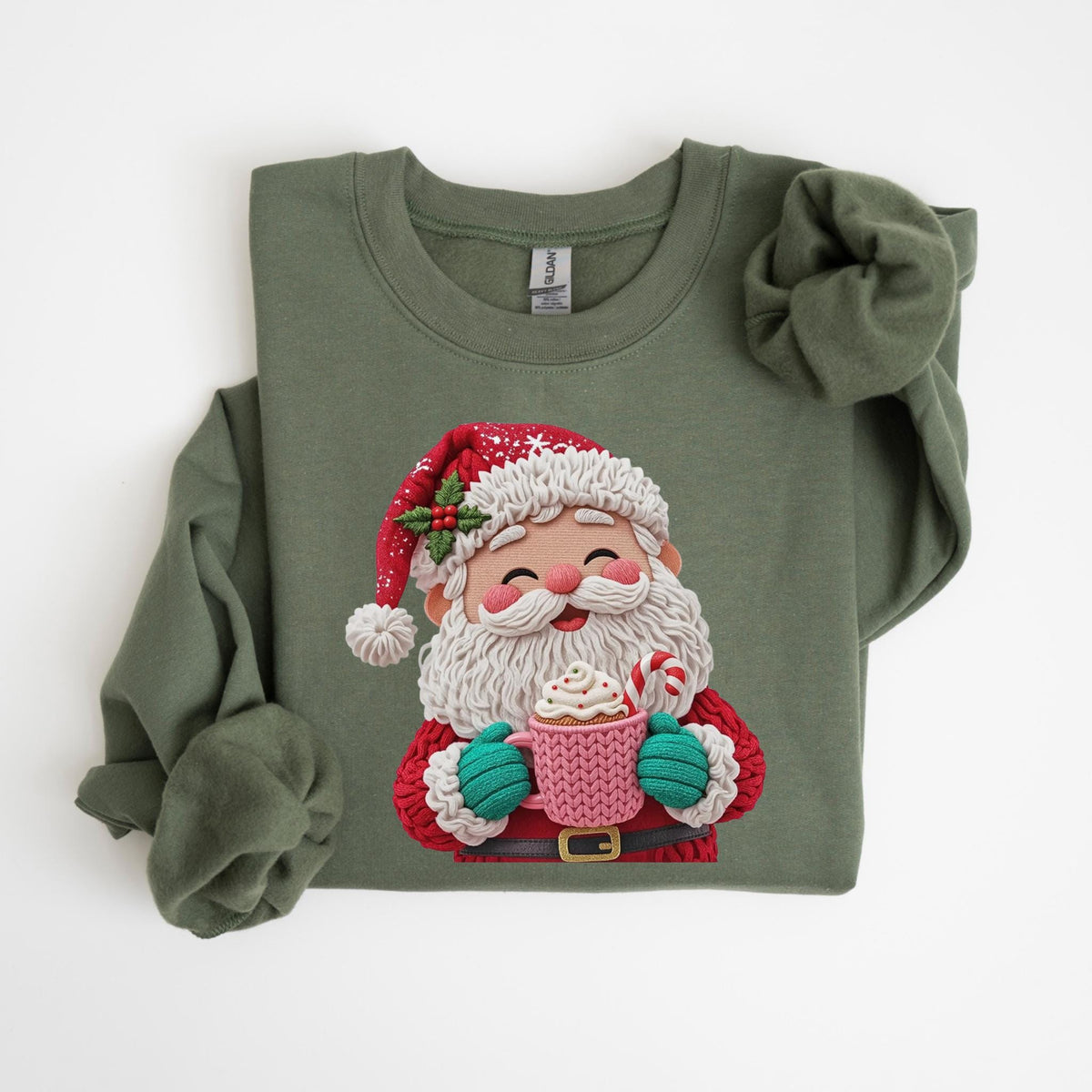 May include: An olive green sweatshirt featuring a cheerful Santa Claus graphic. Santa is depicted with a white beard, red suit, and hat, holding a pink mug with whipped cream and a candy cane. The design is a festive and cozy holiday theme.