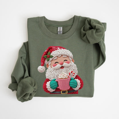 May include: An olive green sweatshirt featuring a cheerful Santa Claus graphic. Santa is depicted with a white beard, red suit, and hat, holding a pink mug with whipped cream and a candy cane. The design is a festive and cozy holiday theme.