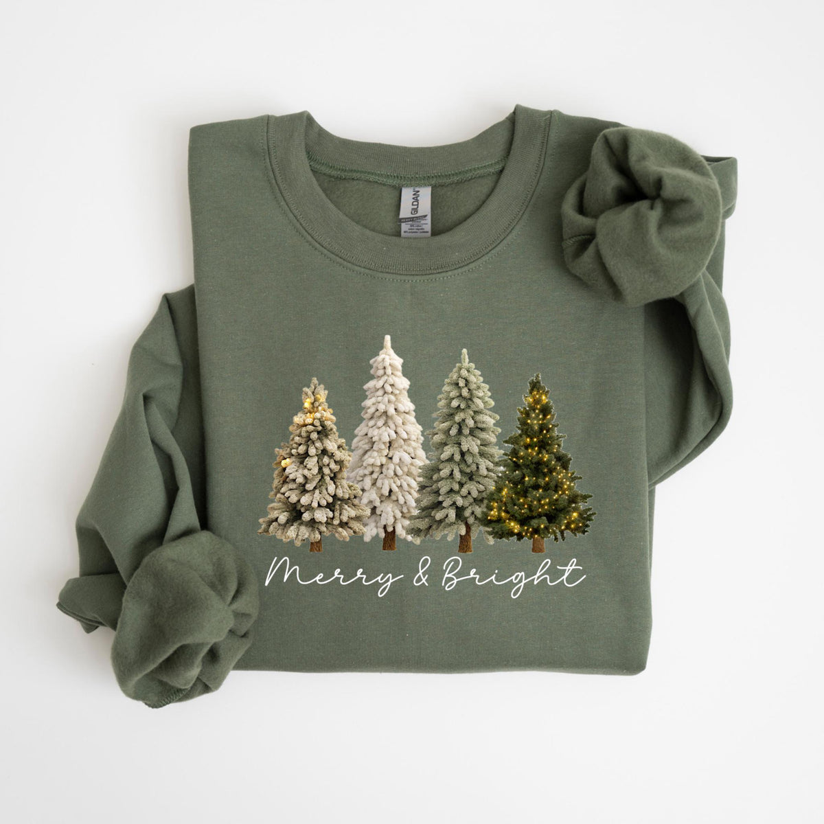 May include: Olive green sweatshirt featuring a graphic of four Christmas trees with string lights. The trees are in varying shades of green and white. The words "Merry & Bright" are written in a script font below the trees.